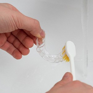 Patient cleaning clear aligner in sink