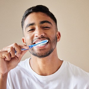 Man smiling while brushing his teeth