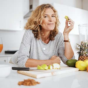 Woman smiling while eating fruit in kitchen
