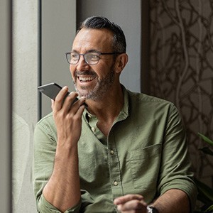 Man with glasses smiling while talking on phone