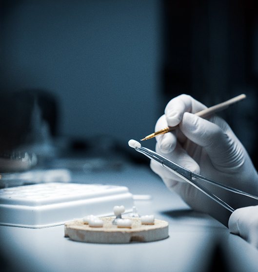 Hands using dental instruments to customize a dental crown