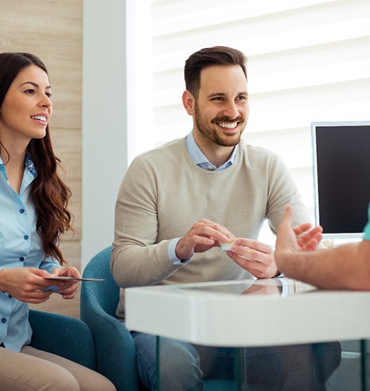 Dentist and couple talking in dental office