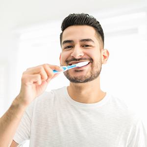 a man brushing his teeth while at home