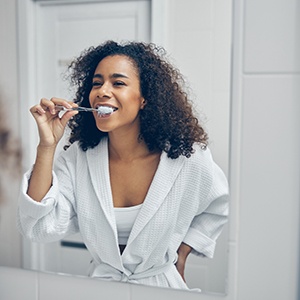 Person brushing teeth around dental implants in Rowlett 
