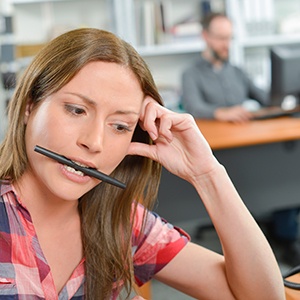 woman with dental implants chewing on pen