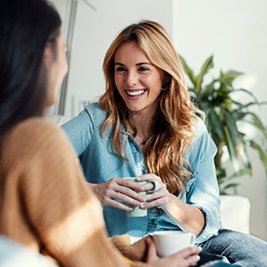 Woman smiling while drinking coffee with friend
