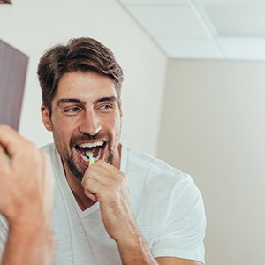 Man smiling while brushing his teeth