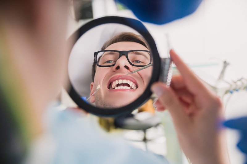 Patient smiling in mirror after cosmetic dentistry