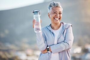 Woman outside holding water bottle smiling
