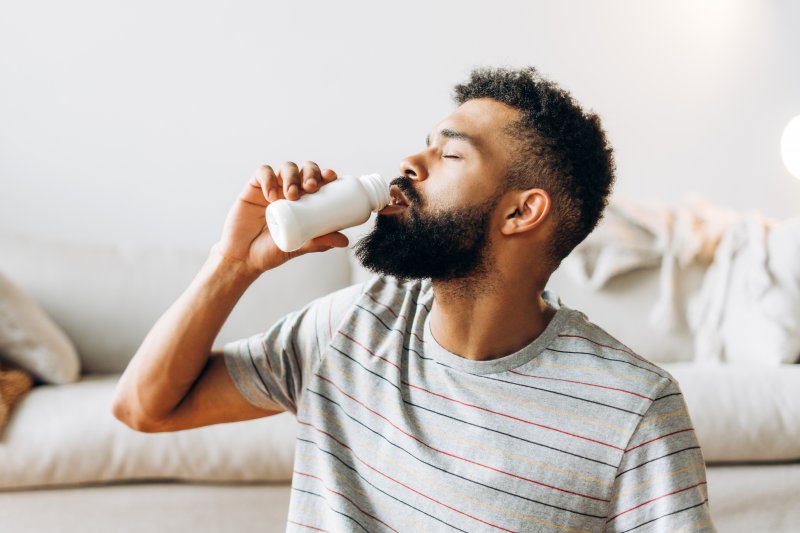 a man drinking a bottle of probiotics at home